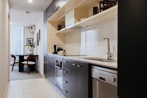 Une cuisine moderne équipée d’un four encastré, d’un lave-vaisselle et d’un coin repas avec une table et des chaises.