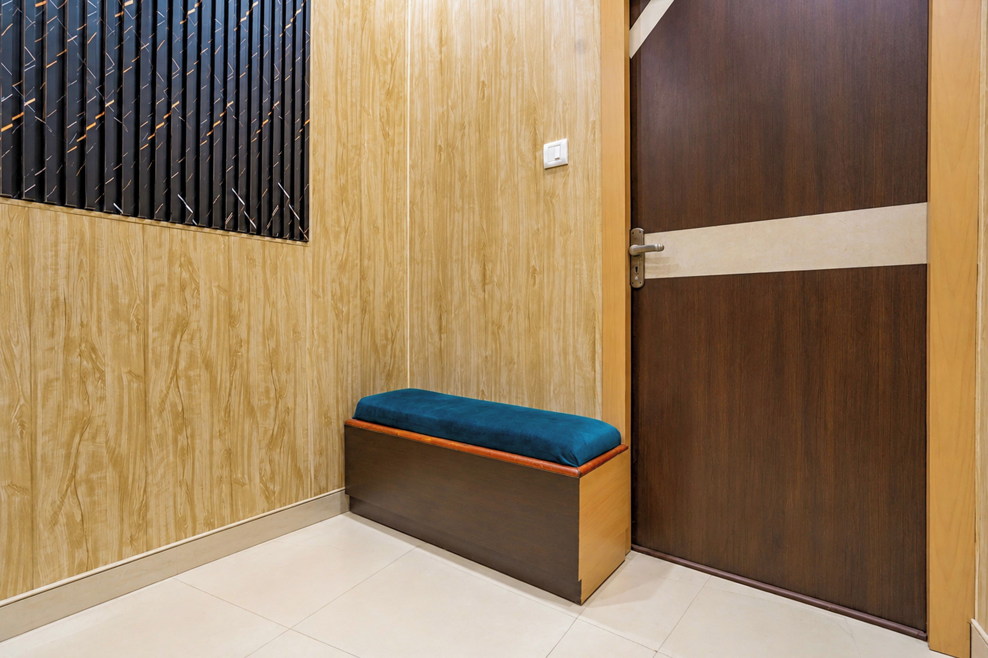 Rincón de una habitación con un banco de madera, una puerta y un zócalo con diseño vertical.