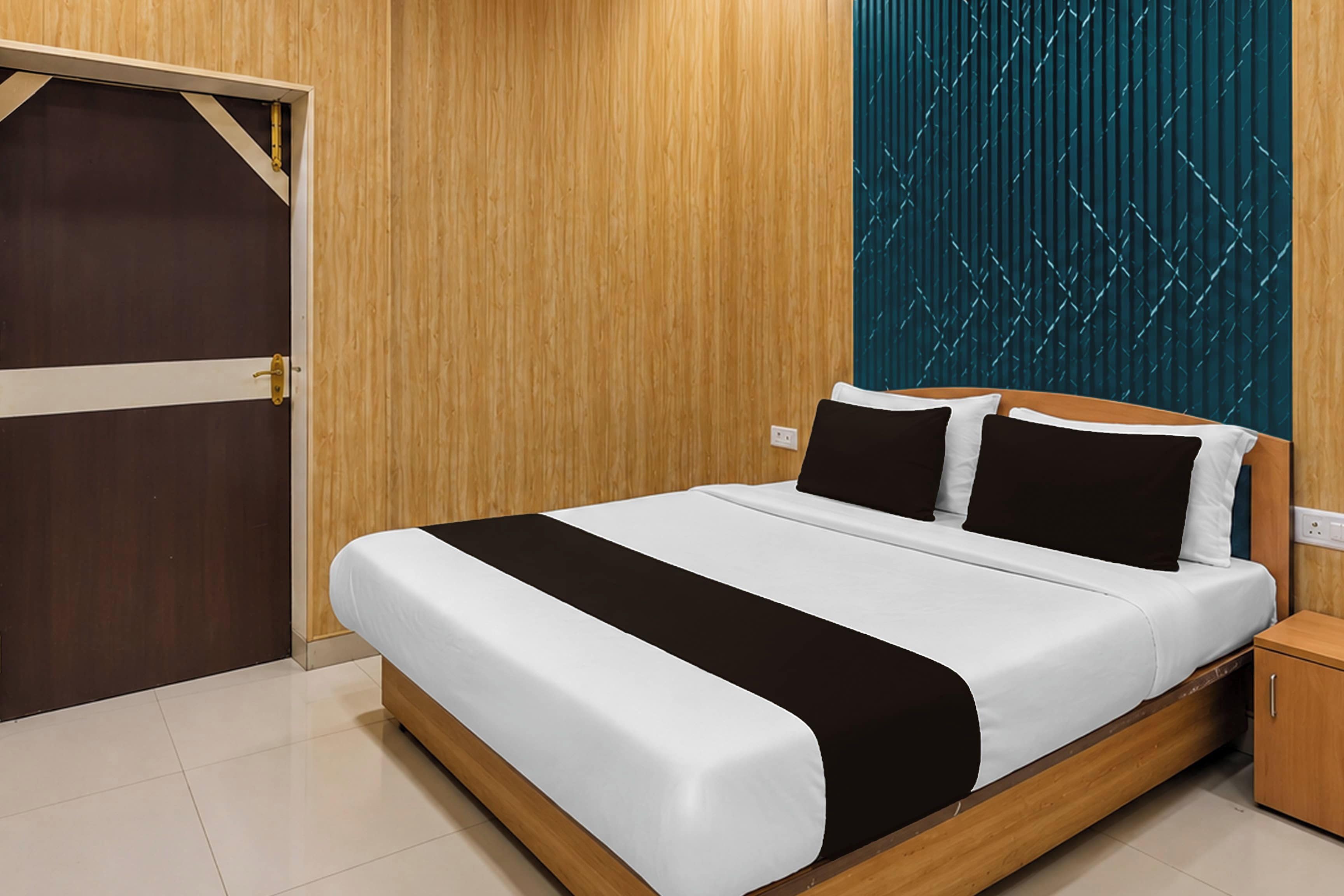 A bedroom with a wooden bed frame, white bedding, and a teal patterned wall.