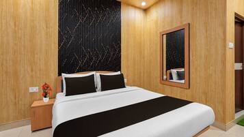 A hotel room with a large bed, a nightstand, a mirror, and a wall with a geometric pattern.