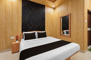 A hotel room with a large bed, a nightstand, a mirror, and a wall with a geometric pattern. - OYO 827785 TJ INTERNATIONAL (Lucknow)