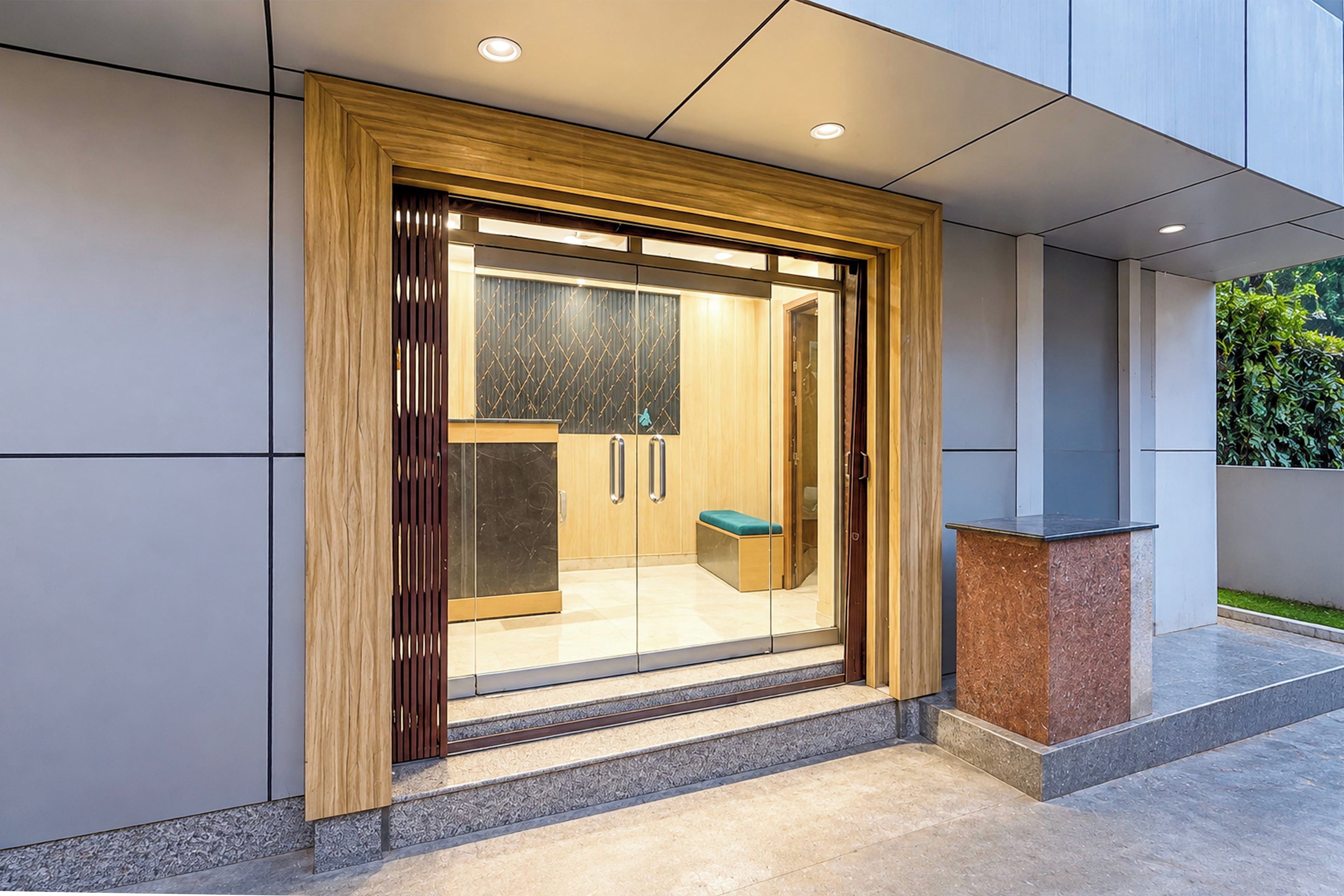 A modern entrance with a wooden frame, glass doors, and a bench outside.