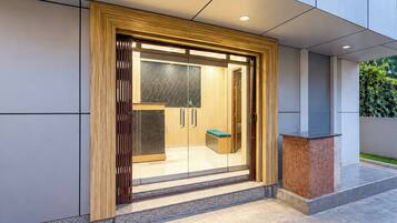 A modern entrance with a wooden frame, glass doors, and a bench outside.