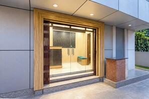 Une entrée moderne avec un cadre en bois, des portes en verre et un banc à l’extérieur.