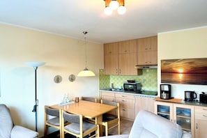 A compact kitchen with wooden cabinets, a microwave, and a coffee maker. - Holiday apartment in Wyk with swimming pool (Wyk)