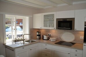 A modern kitchen with white cabinetry, a built-in oven, and a window overlooking a street. - Holiday apartment with 1 bedroom (Wrixum)