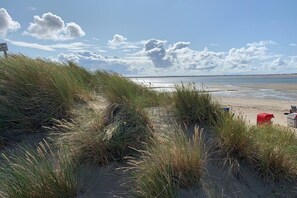 Een strand met duinen en een heldere lucht.