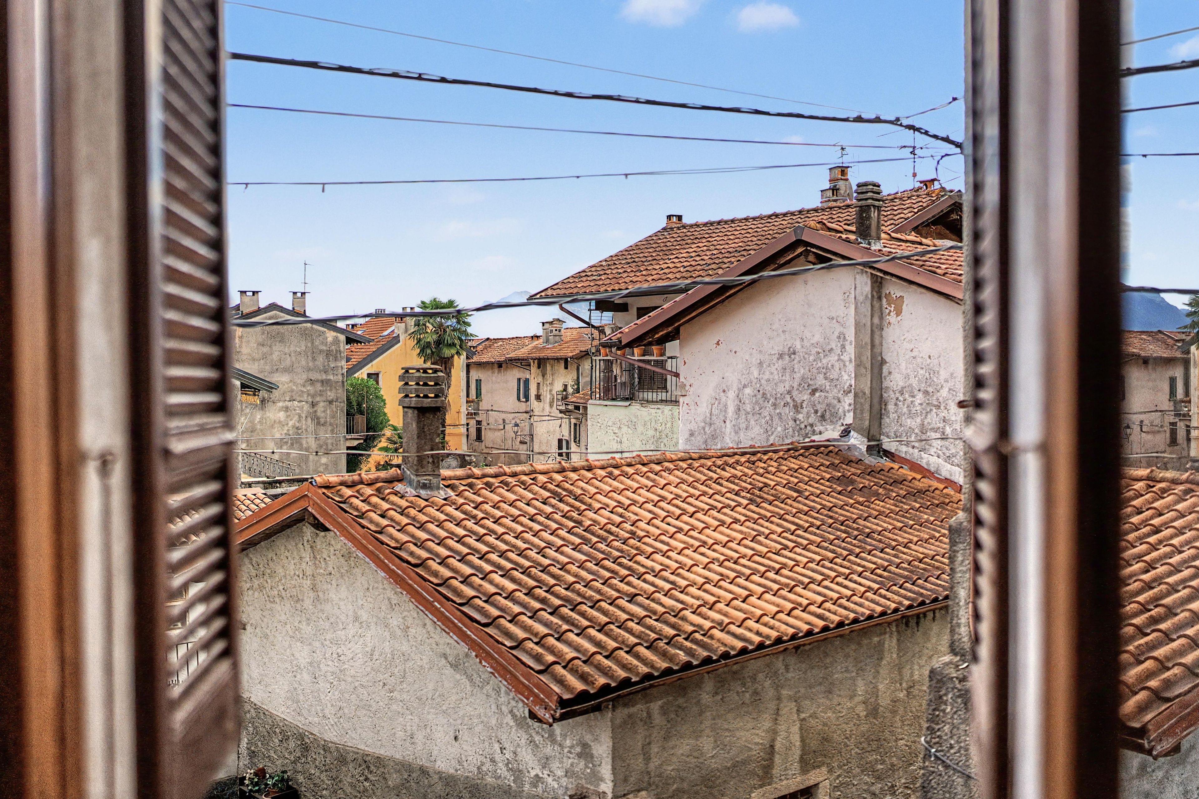 Vue d’un quartier résidentiel avec des toits recouverts de tuiles en terre cuite, un mélange de styles architecturaux et des lignes électriques apparentes.