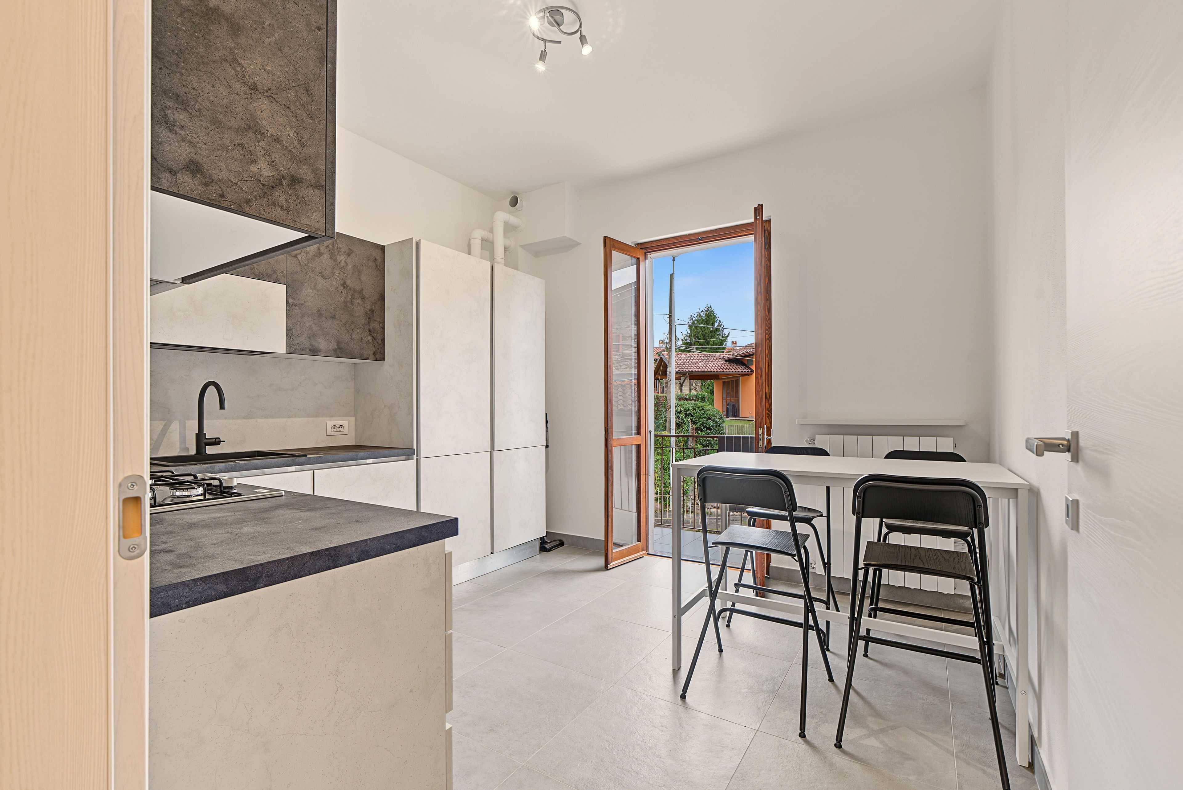 A modern kitchen with a built-in oven, a sink, and a dining area with a table and chairs.