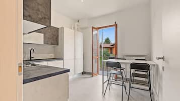 A modern kitchen with a built-in oven, a sink, and a dining area with a table and chairs.