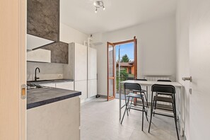 Una cocina moderna con horno empotrado, un lavamanos y una zona de comedor con mesa y sillas.