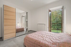 Una camera da letto con un letto grande, un armadio e una porta scorrevole in vetro che dà su un balcone.