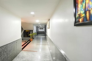 A hallway with a marble floor, potted plants, and a framed picture on the wall. - 9 Star Hotel & Restaurant (Agra)