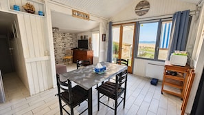 A room with a dining table, chairs, a television, and a view of the beach. - The sea breeze, ocean views, and direct access to the beach (Saint-Côme-de-Fresné)