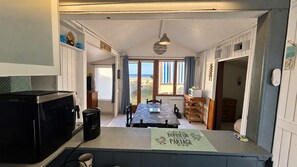 A compact kitchen with a dining area, a view of the beach, and a sign indicating a beachside location. - The sea breeze, ocean views, and direct access to the beach (Saint-Côme-de-Fresné)