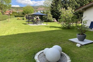 A well-maintained garden with a barbecue area, stone sculptures, and a potted plant. - Holiday apartment with 1 bedroom (Bodenmais)