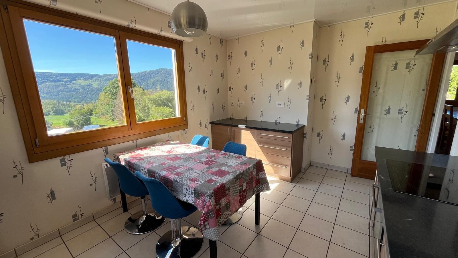Une cuisine avec une table à manger, des chaises et une vue sur l’extérieur.