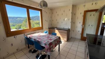Une cuisine avec une table à manger, des chaises et une vue sur l’extérieur.