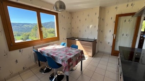 Une cuisine avec une table à manger, des chaises et une vue sur l’extérieur.