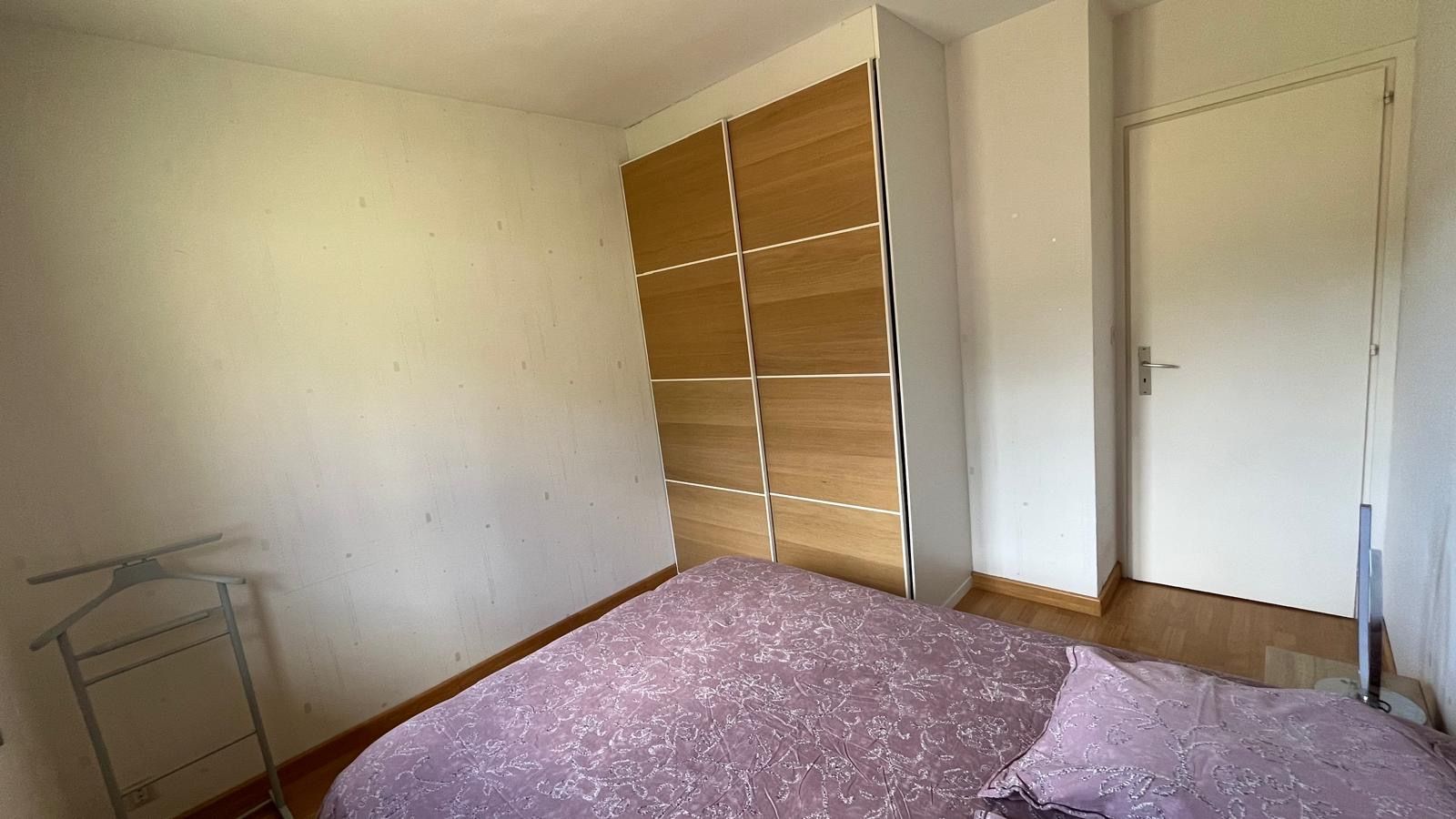 A bedroom with a bed, a wardrobe, and a door.