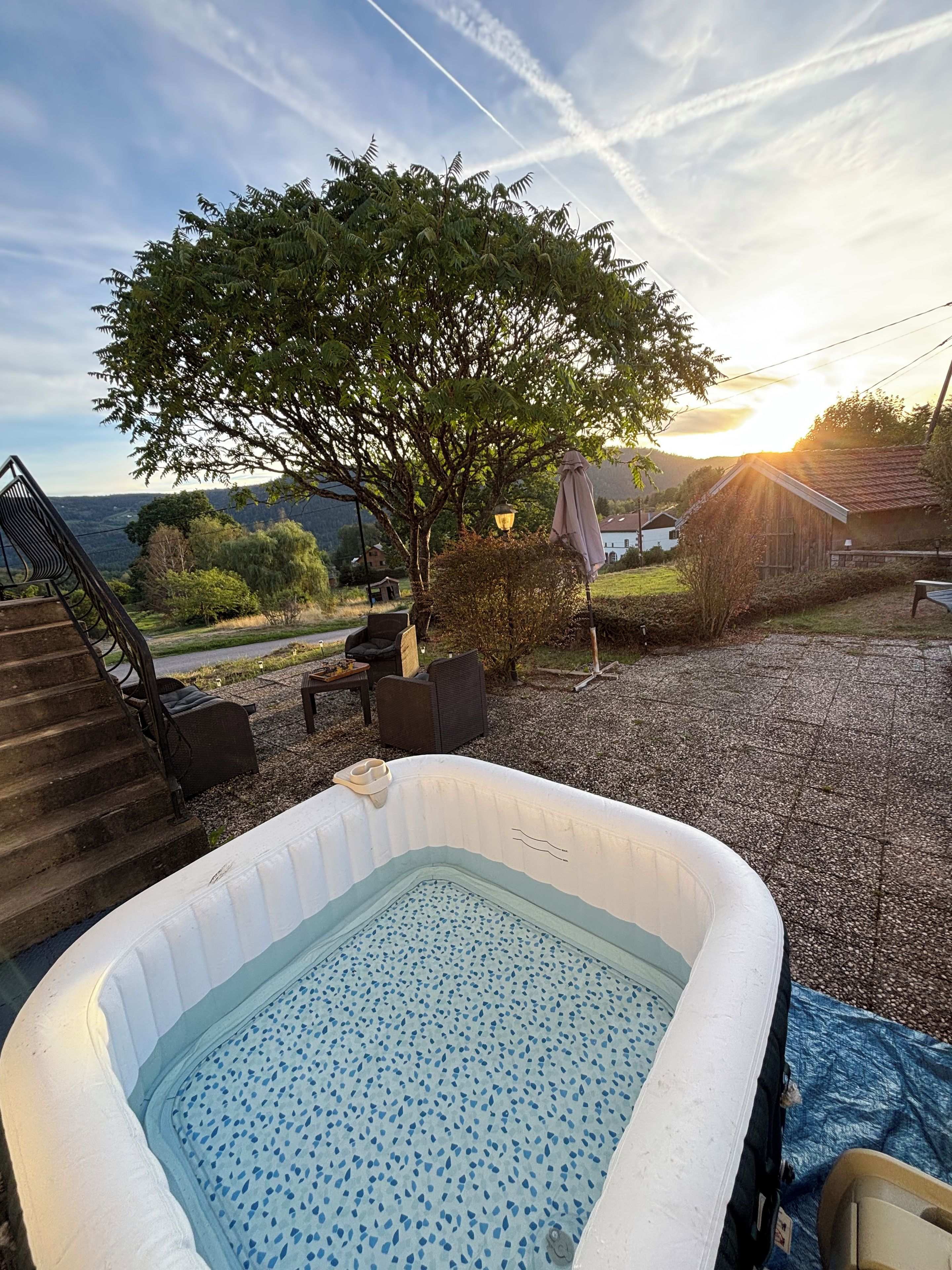 Un bain à remous avec vue sur un arbre et une maison en arrière-plan.
