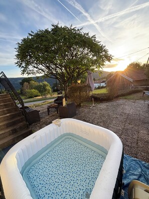 A hot tub with a view of a tree and a house in the background. - Beautiful vacation rental with mountain views for 6 people, featuring a pool and hot tub (Basse-sur-le-Rupt)