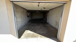 Un garage avec un plancher en béton, un ventilateur de plafond et une porte donnant sur un mur extérieur.