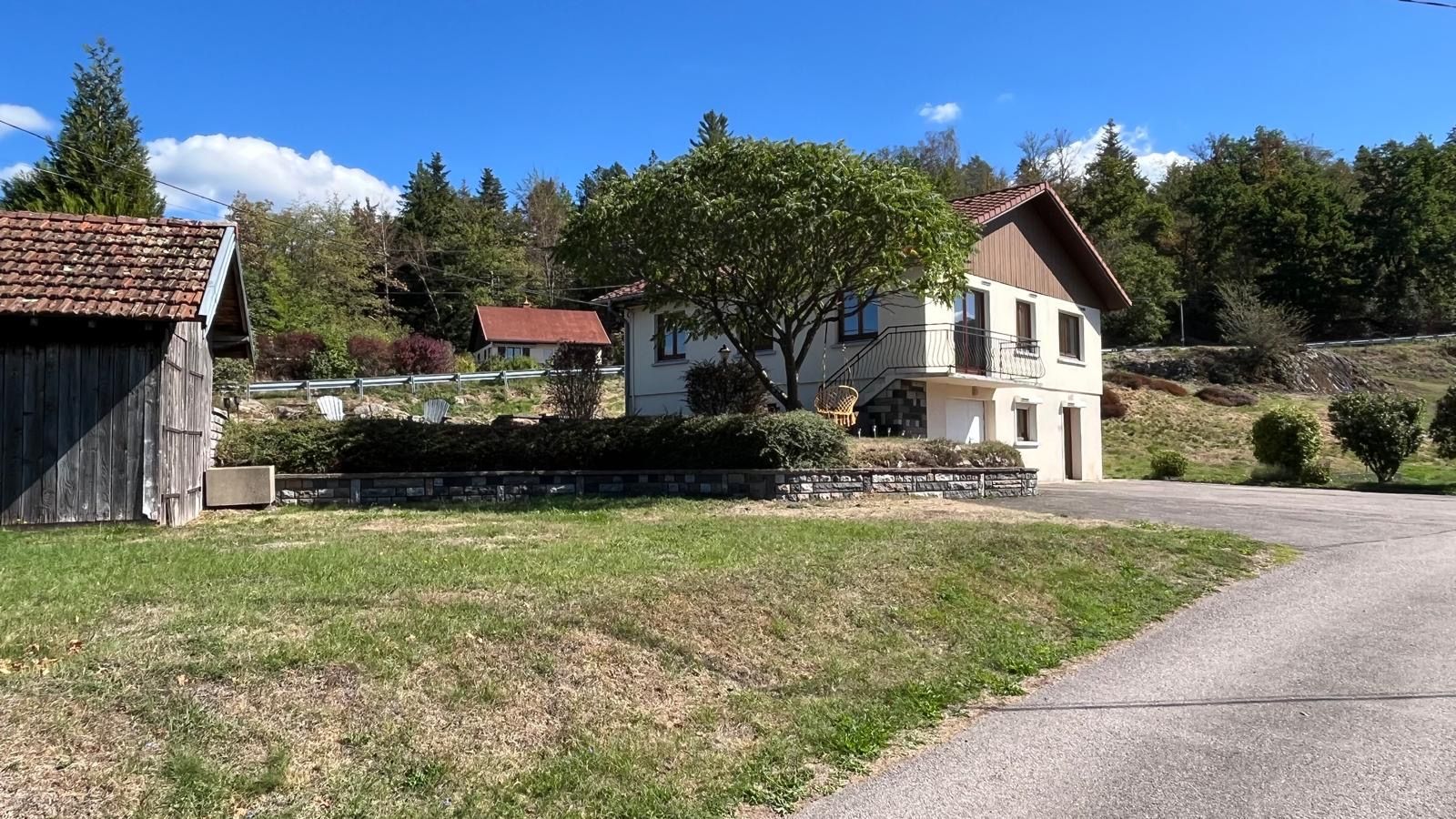 Un quartier résidentiel comprenant une maison à deux étages, une grange en bois et une allée pavée.