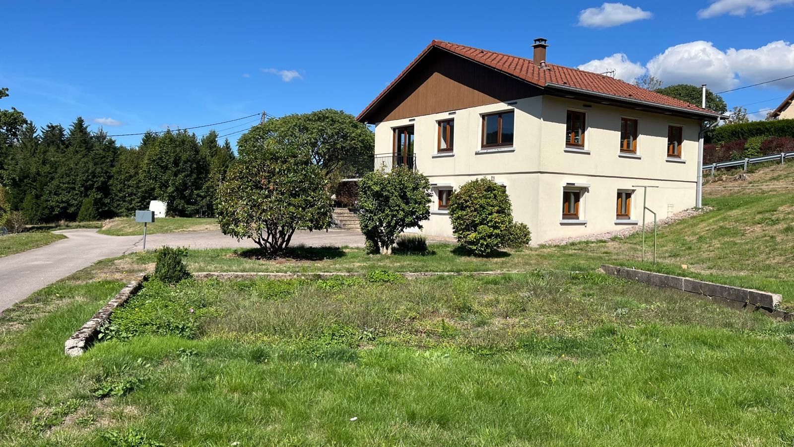 Une maison à deux étages avec un toit en pente, une boîte aux lettres et une allée pavée.