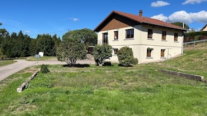Une maison à deux étages avec un toit en pente, une boîte aux lettres et une allée pavée.