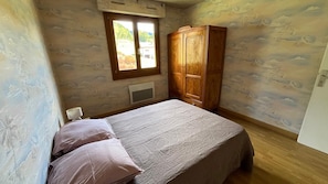 Une chambre à coucher avec un lit, une armoire, une fenêtre et un radiateur.