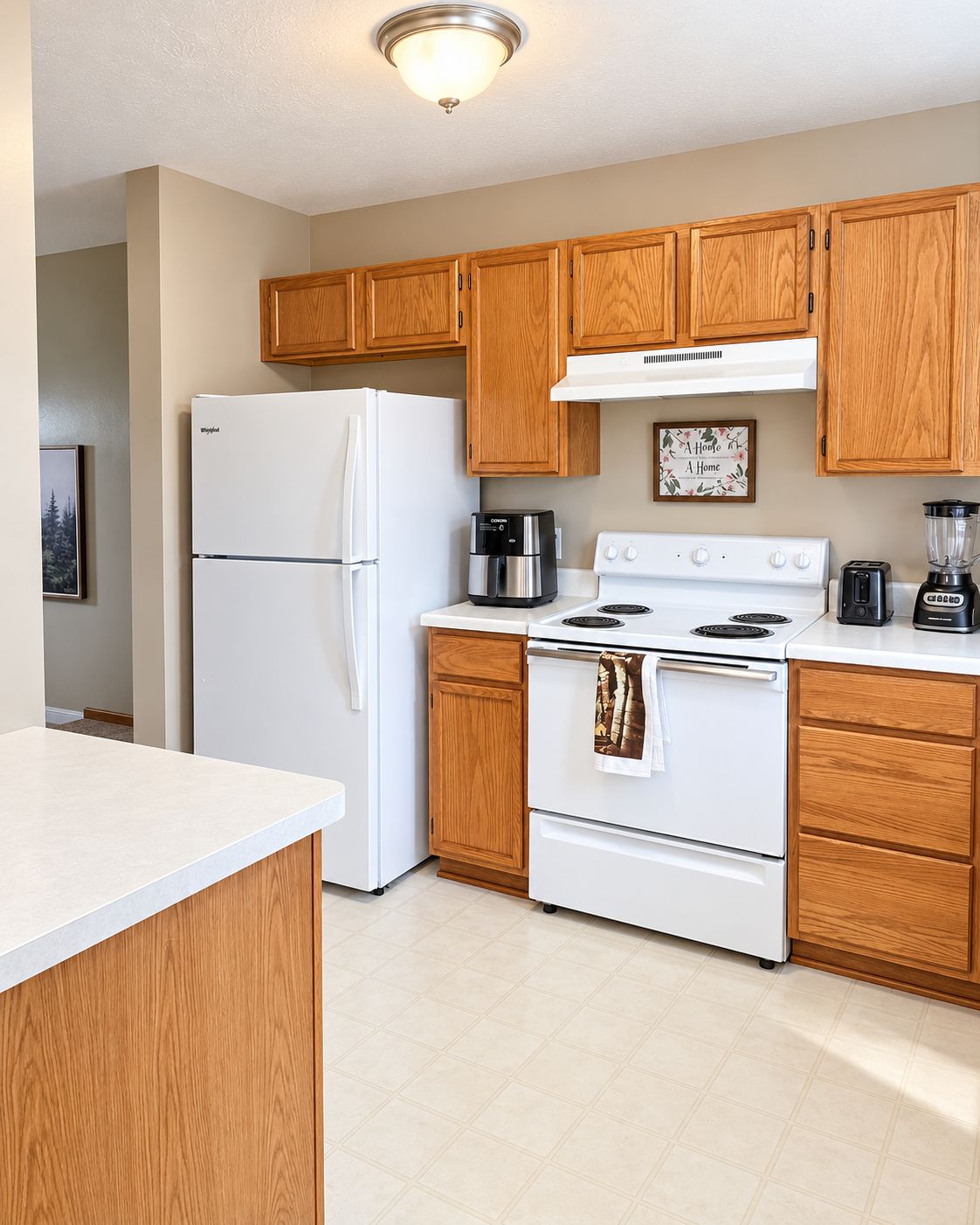 A modern kitchen with wooden cabinets, a white refrigerator, a stove, and a coffee maker.