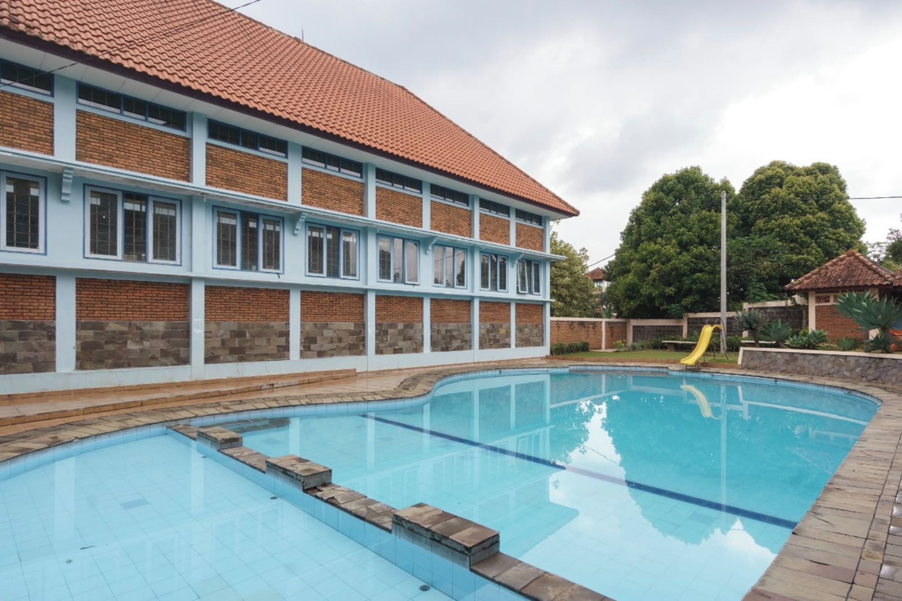 A swimming pool with a brick building in the background.