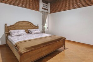 Ein Schlafzimmer mit einem hölzernen Bett, weißen Wänden, einer Ziegeldecke und einem Fenster mit Vorhängen.