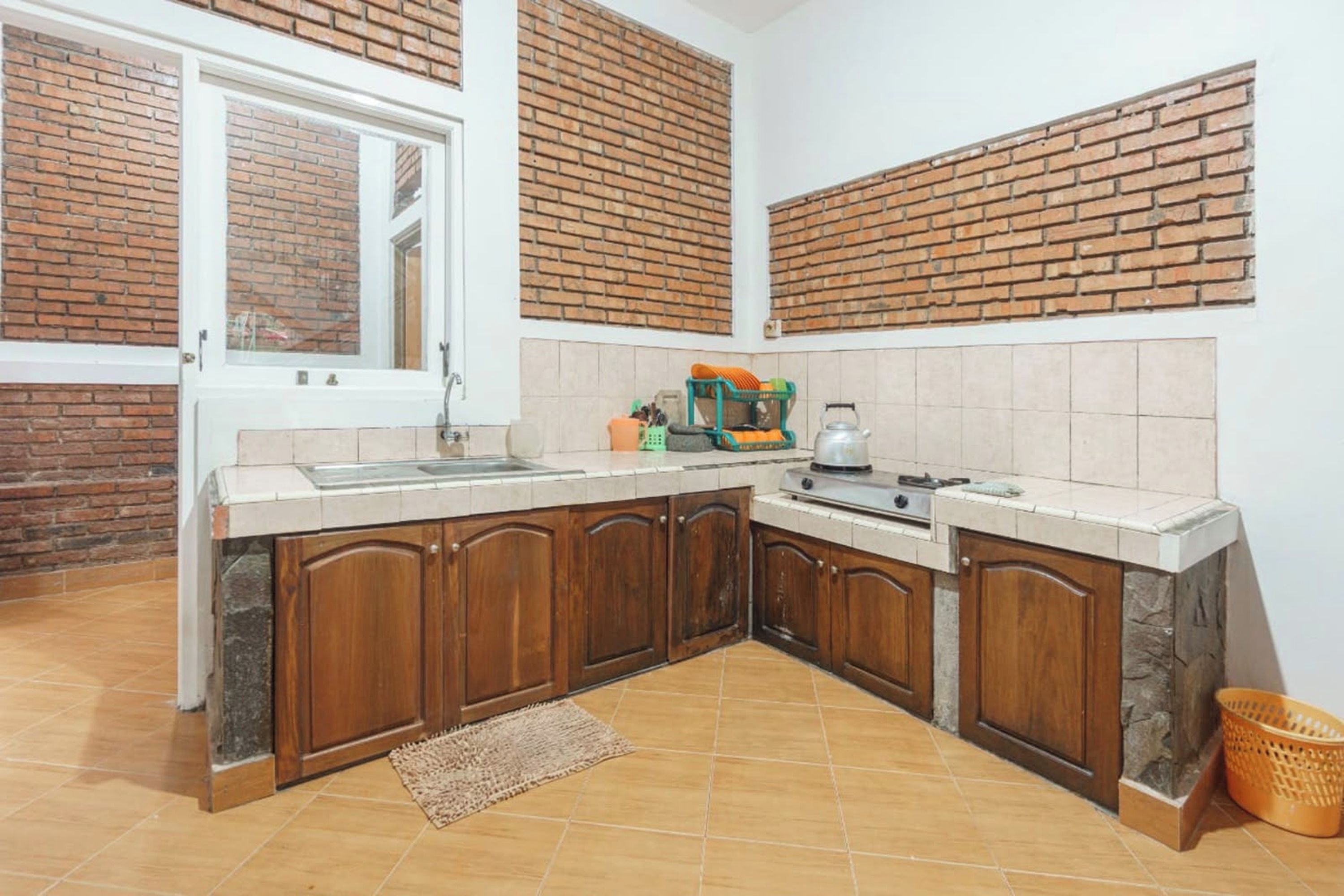 A kitchen with wooden cabinets, a built-in stove, and a window with a view of a brick wall.