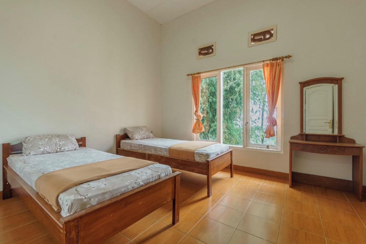 Ein Schlafzimmer mit zwei Holzbett, einem Nachttisch aus Holz und einem Fenster mit Vorhängen.