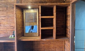 Interior de una cabaña de madera con un banco empotrado y un estante pequeño.