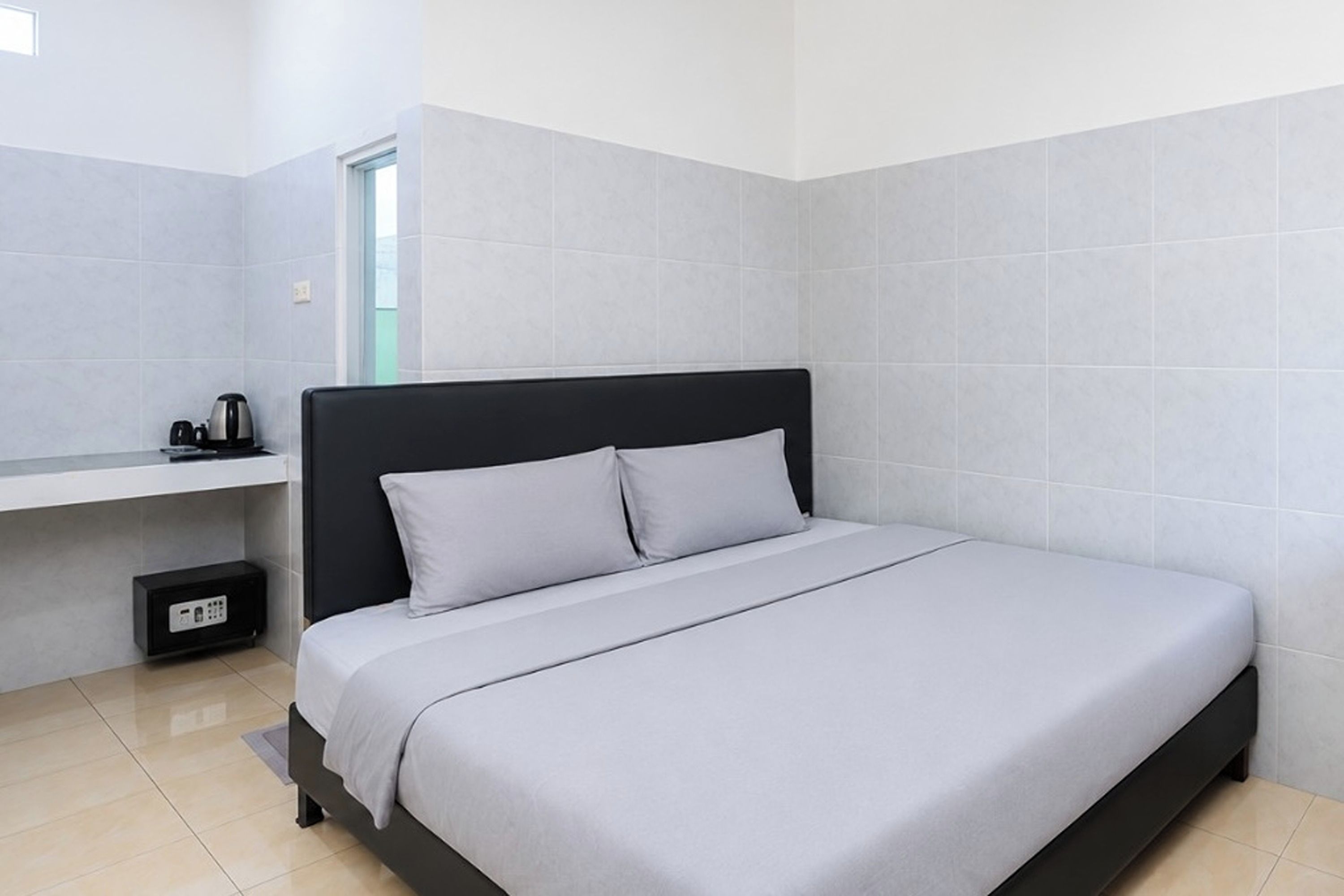 Ein modernes Schlafzimmer mit einem Einzelbett, einem Nachttisch, einer Steckdose und einem Fenster.