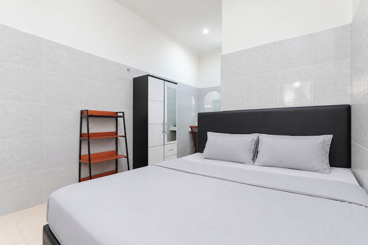 A modern bedroom with a large bed, a wardrobe, and a built-in shelf unit.
