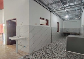 A bathroom with a marble wall, a sink, a window, and a tiled floor. - Ava Villa Pulosari (Kendari)