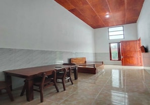 Une pièce spacieuse avec une table et des chaises en bois, un banc et une grande armoire.