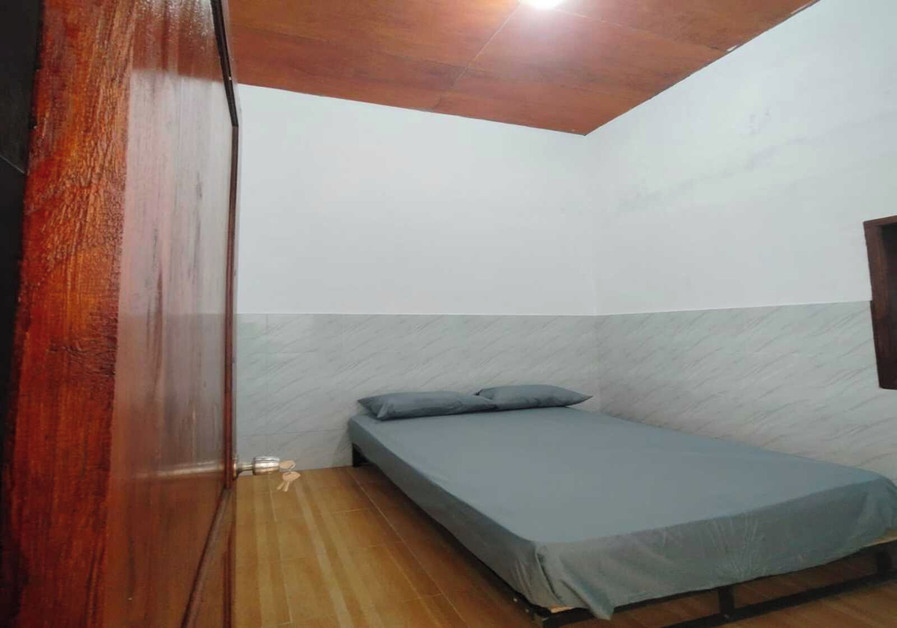 A small room with a single bed, wooden flooring, and a sloped ceiling.