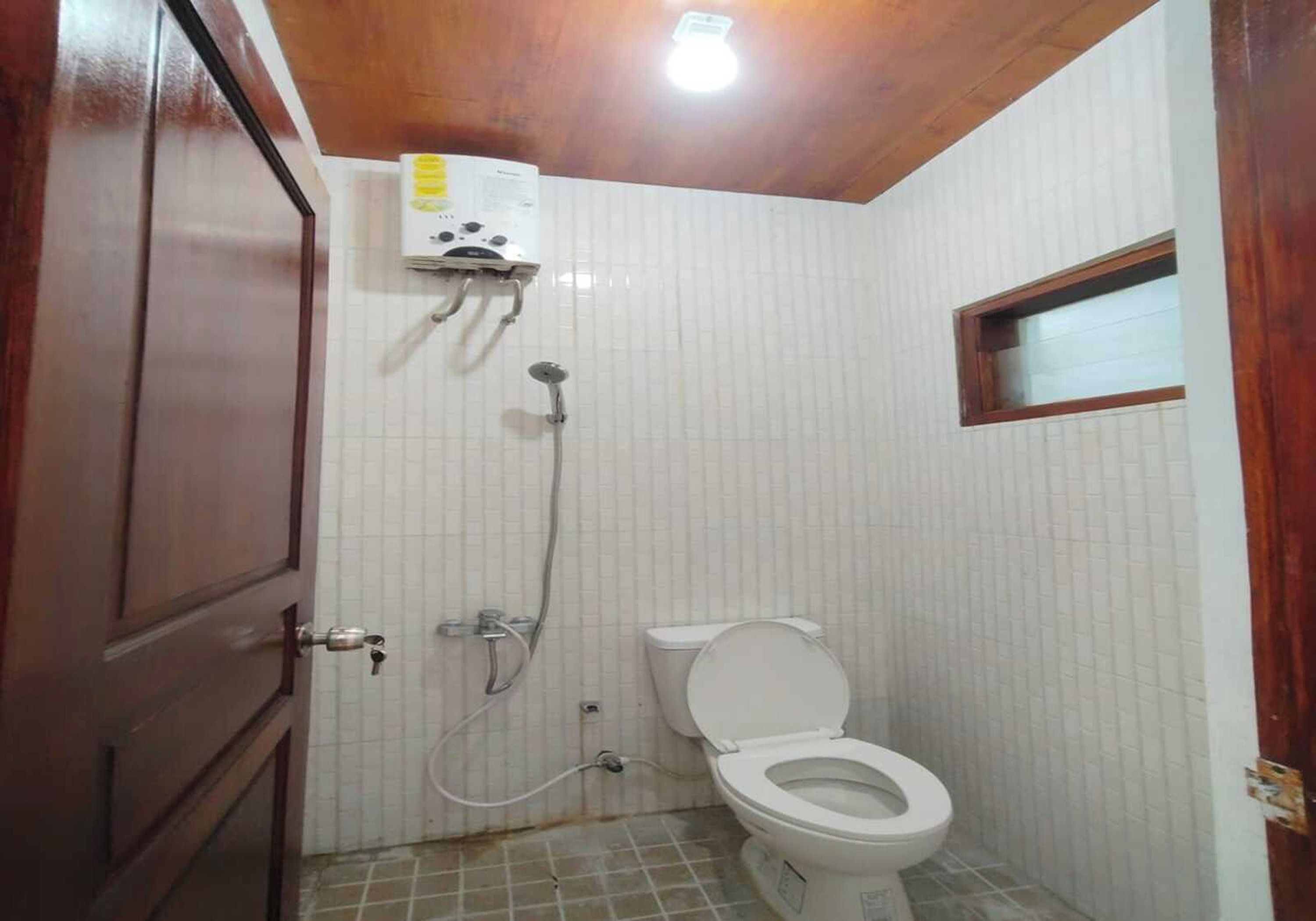 A small bathroom with a toilet, a shower, and a wall-mounted heater.
