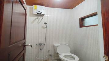 A small bathroom with a toilet, a shower, and a wall-mounted heater.