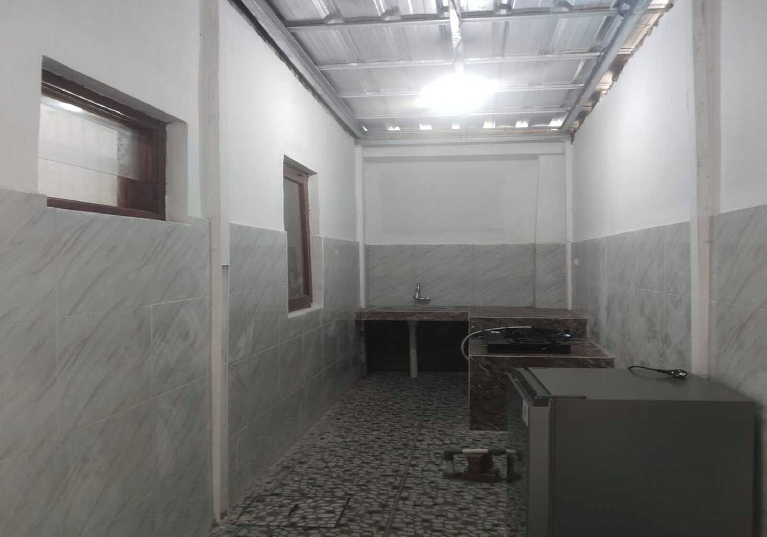 A narrow bathroom with a tiled floor, a sink, and a mirror.