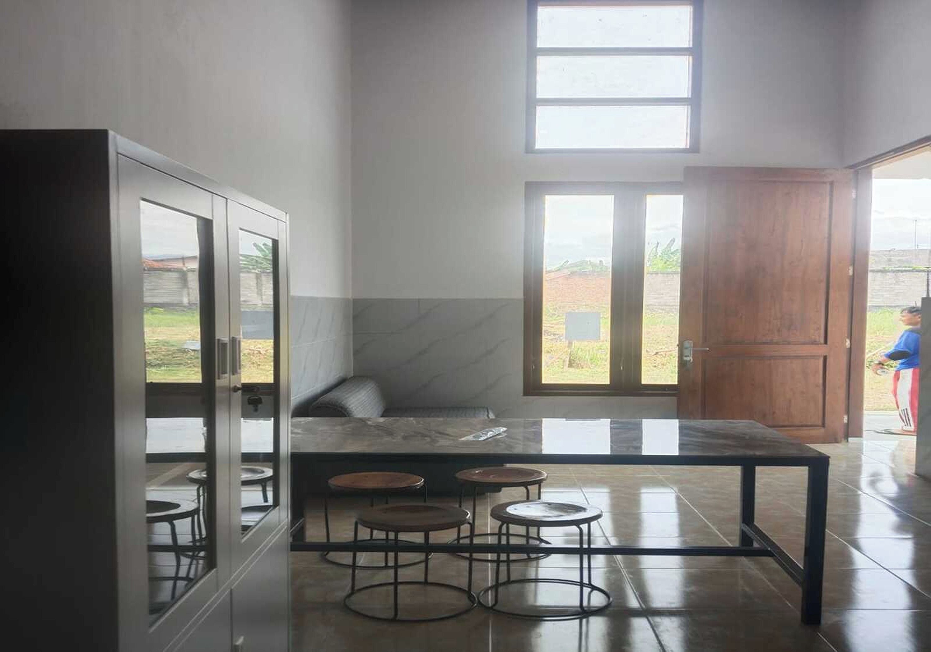 A modern kitchen with a marble countertop, a built-in cabinet, and a large window.