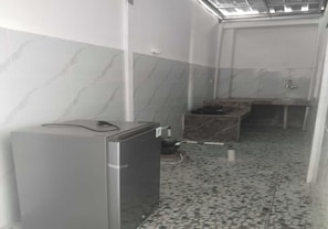 A narrow hallway with a tiled floor, a small refrigerator, and a sink area.
