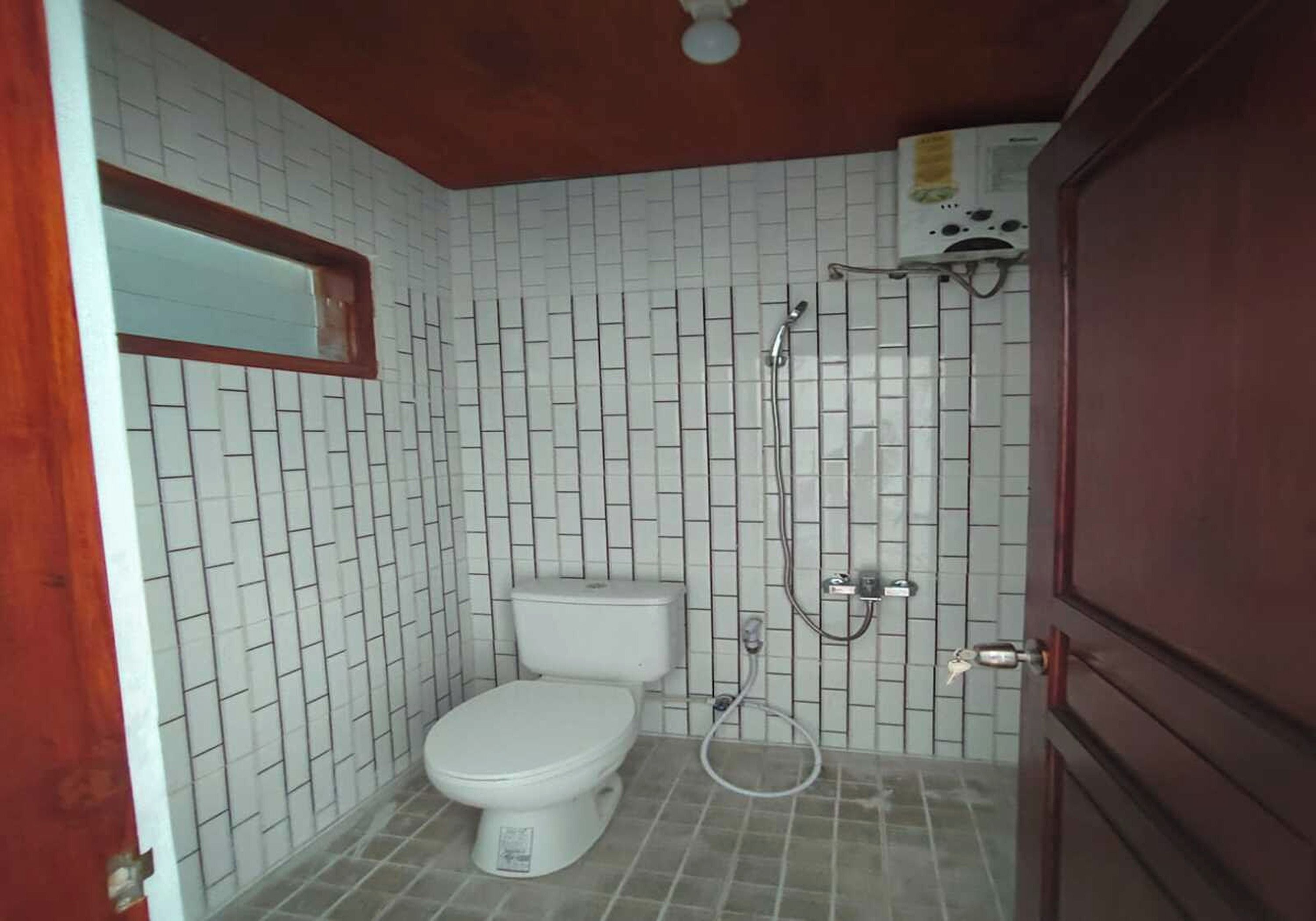A small bathroom with a toilet, a shower, and a tiled wall.