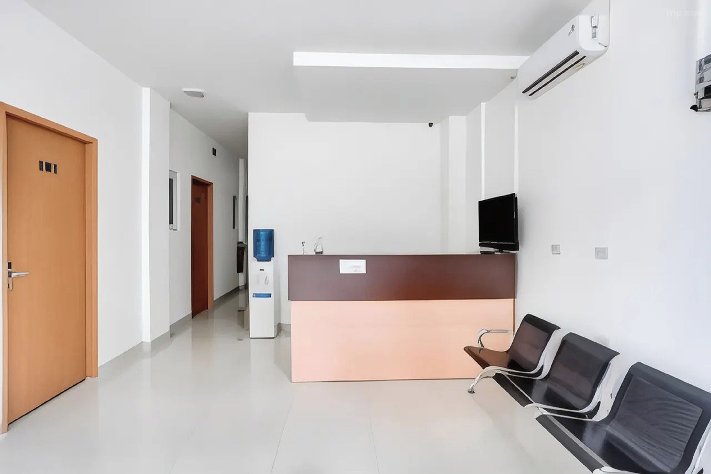 A reception area with a reception desk, a water dispenser, a television, and a seating area with chairs.
