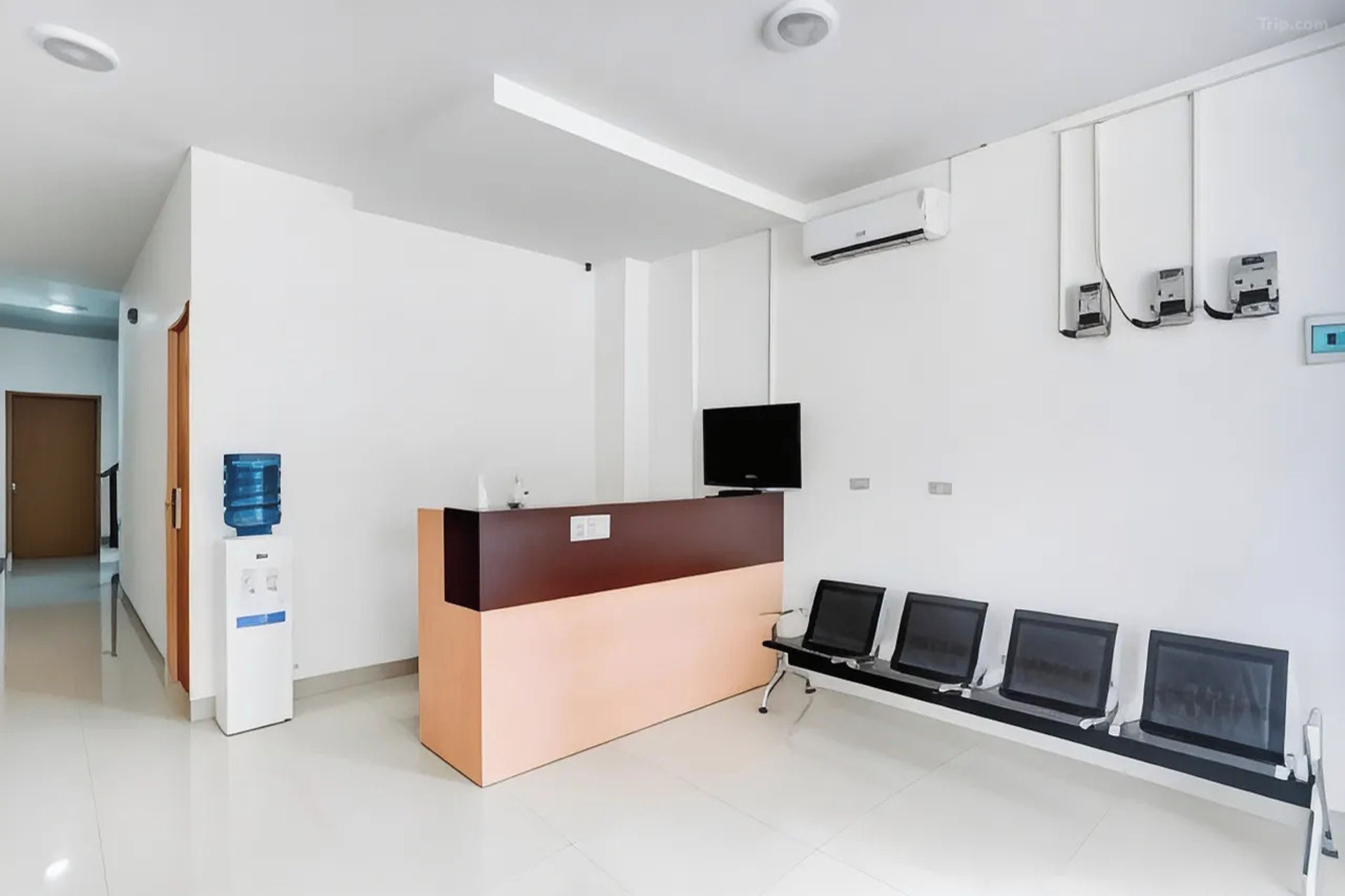 A reception area with a counter, a water dispenser, a flat-screen TV, and a row of computer monitors.